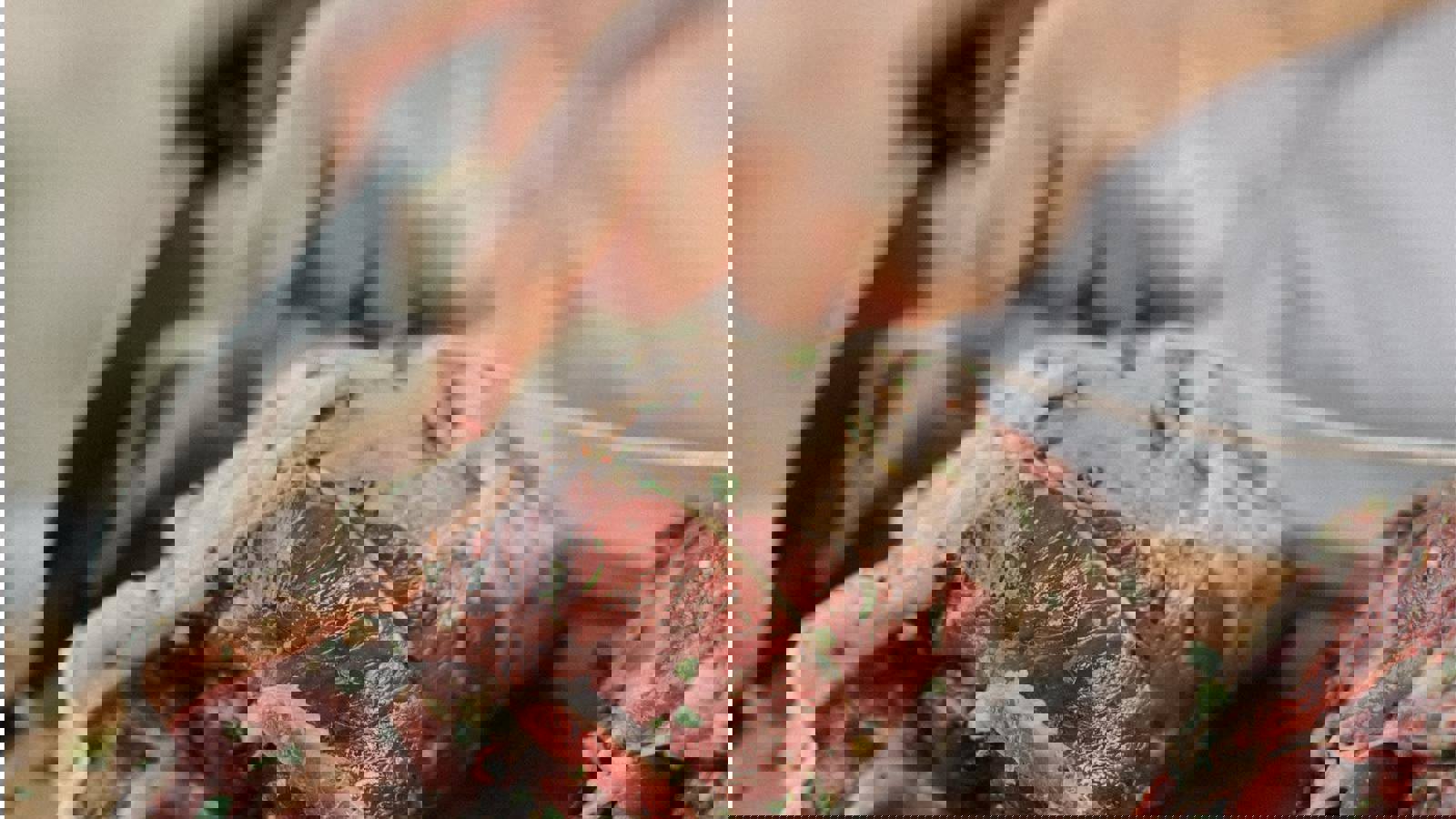 Person preparing raw red meat for cooking