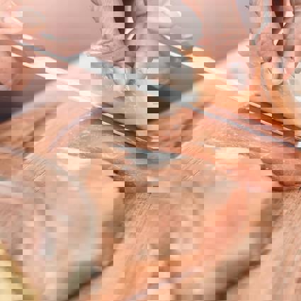 Person slicing raw chicken breast with a knife