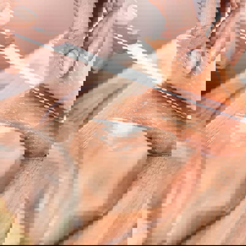 Person slicing raw chicken breast with a knife