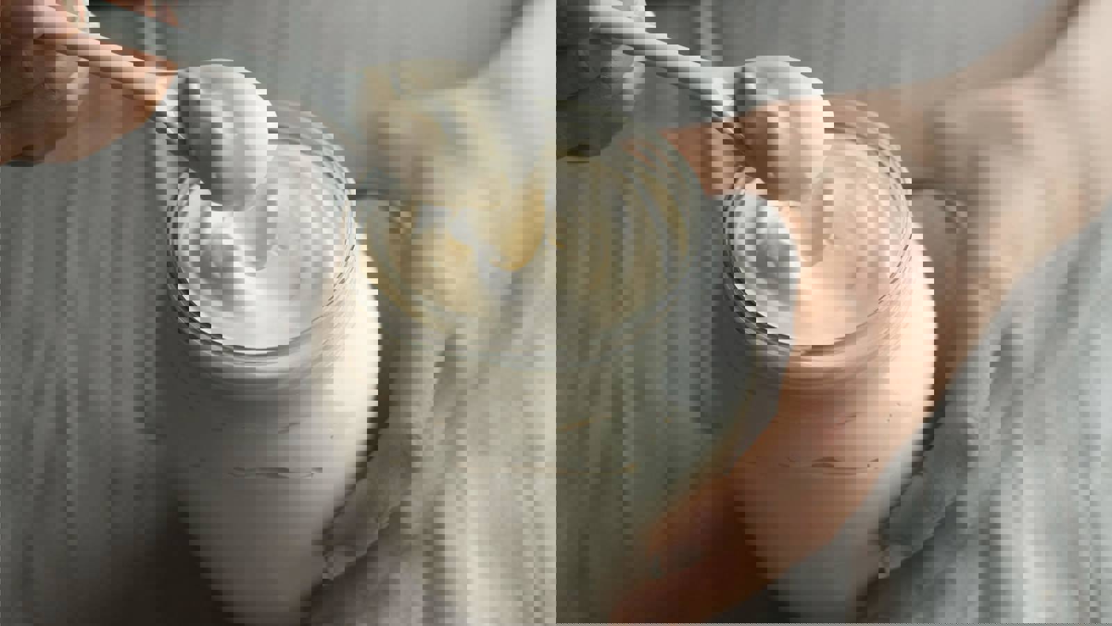 Female hands with spoon taking mayonnaise from a jar