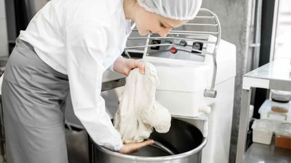 Baker Handling Dough In A Commercial Bakery