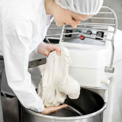Baker Handling Dough In A Commercial Bakery