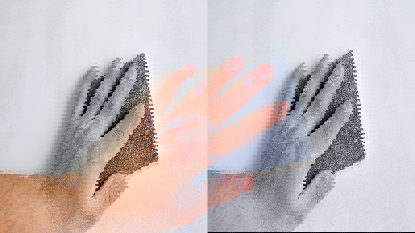 Person Sanding A Wall