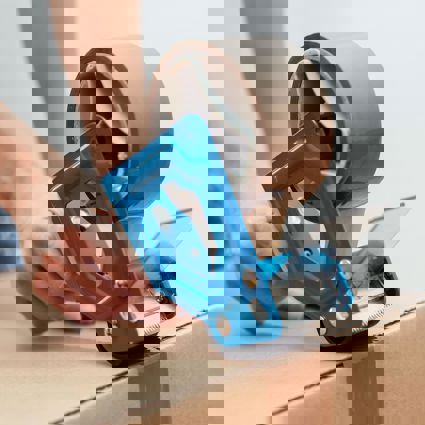 Person taping a cardboard box closed with brown tape