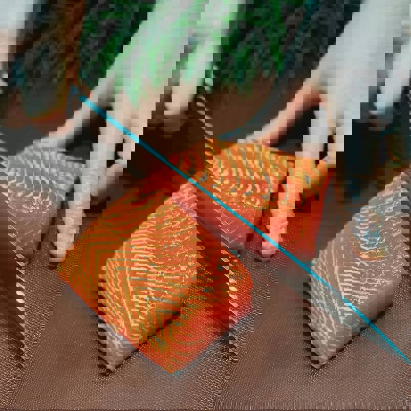 Person cutting raw salmon fillet