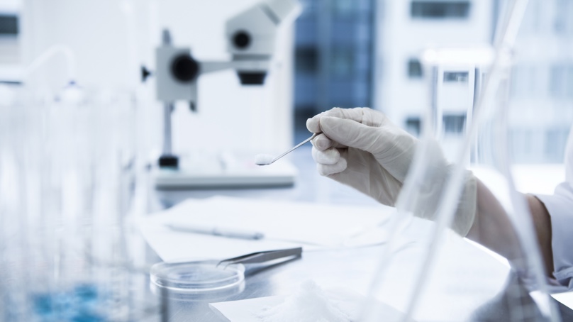 Technician Scooping White Powder In A Laboratory