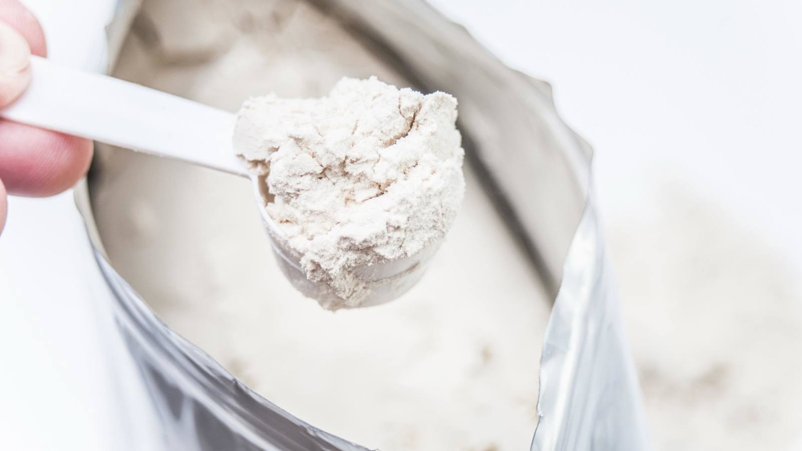 Person scooping protein powder from a bag