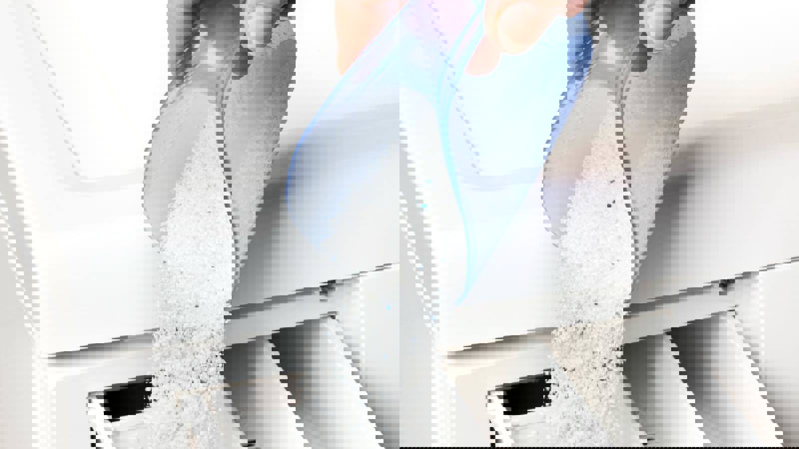 Person pouring washing powder into washing machine drawer