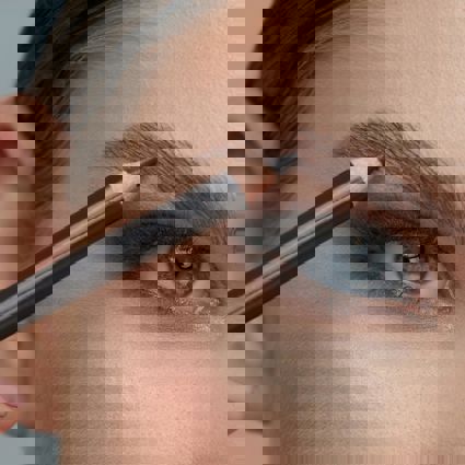 Person using a eyebrow pencil to define eyebrows 