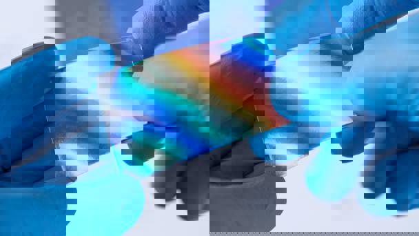 Hands Wearing Blue Gloves Holding Reflective Material