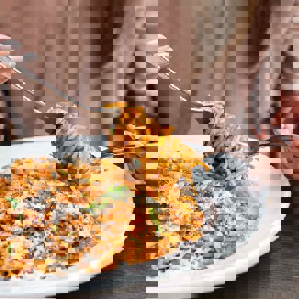 Person twirling cooked spaghetti onto a fork