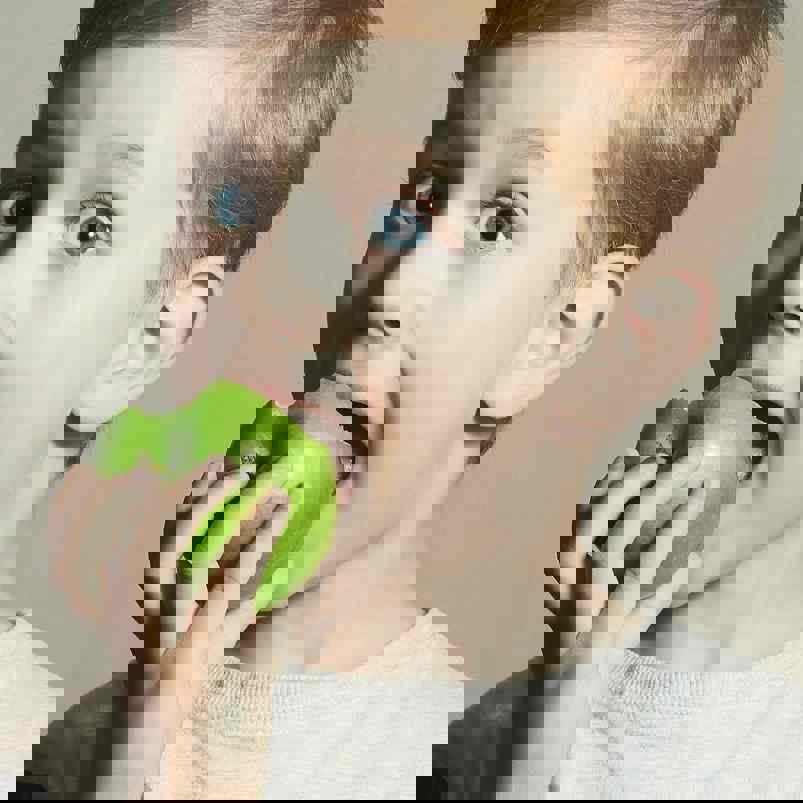 Child biting into a crunchy green apple