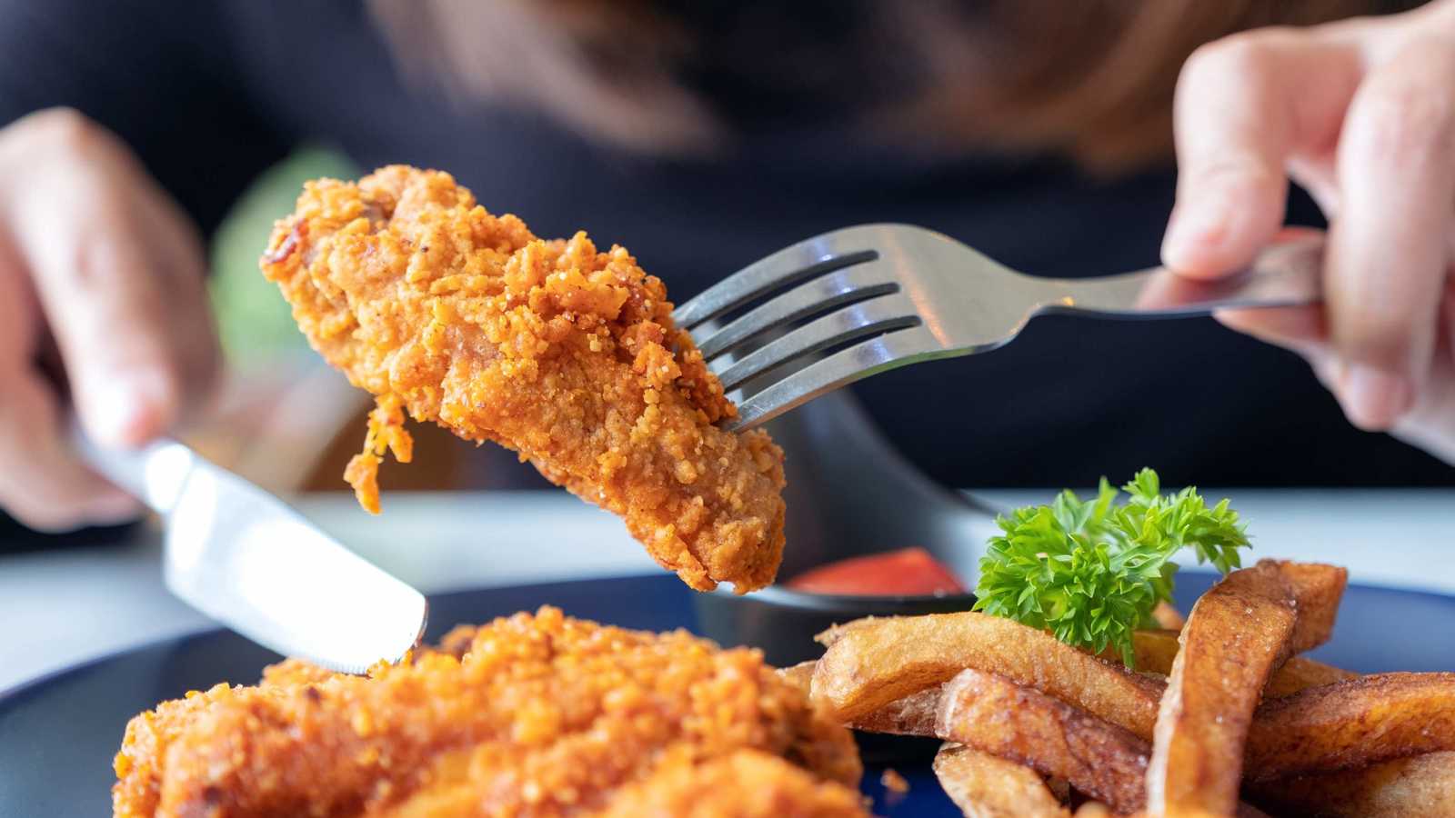 Person picking up fried chicken with a fork