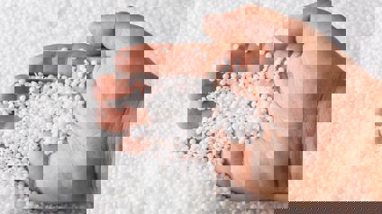 Person Scooping Polymers In Pellet Form With Hand