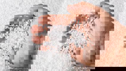 Person Scooping Polymers In Pellet Form With Hand