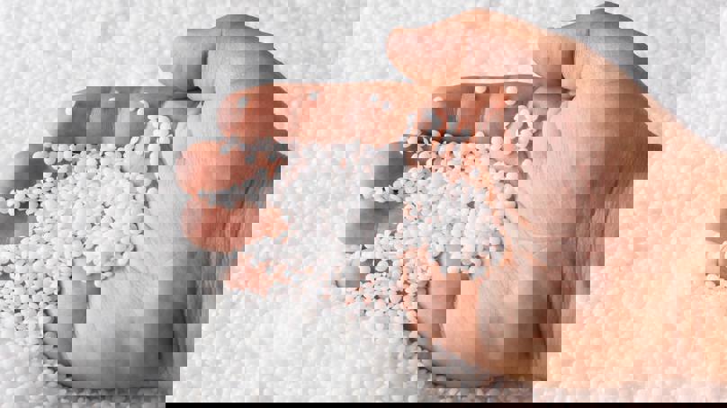 Person Scooping Polymers In Pellet Form With Hand