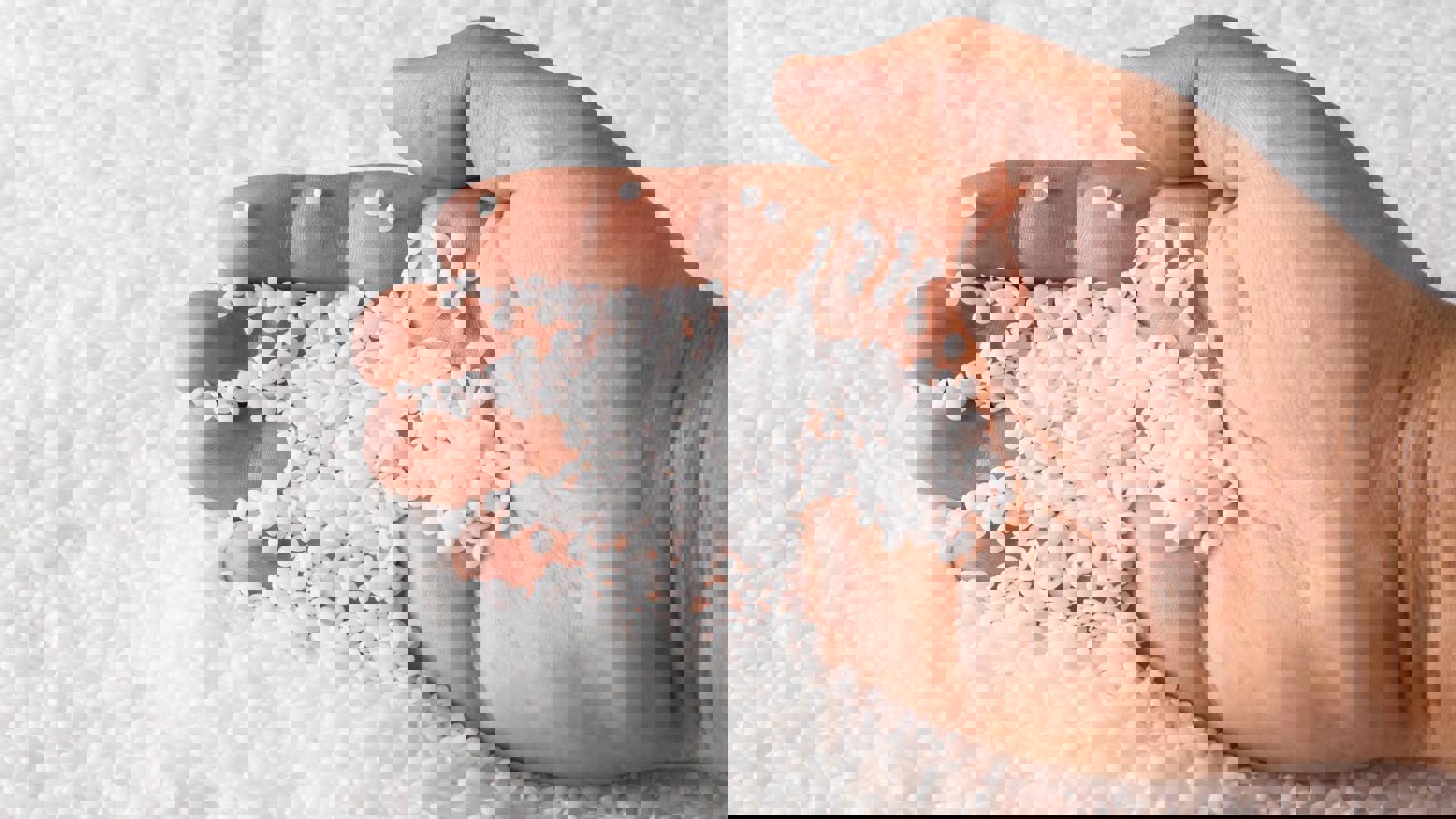 Person scooping polymers in pellet form with hand