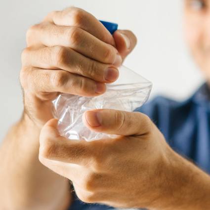 Person crushing a single-use plastic bottle with their hands